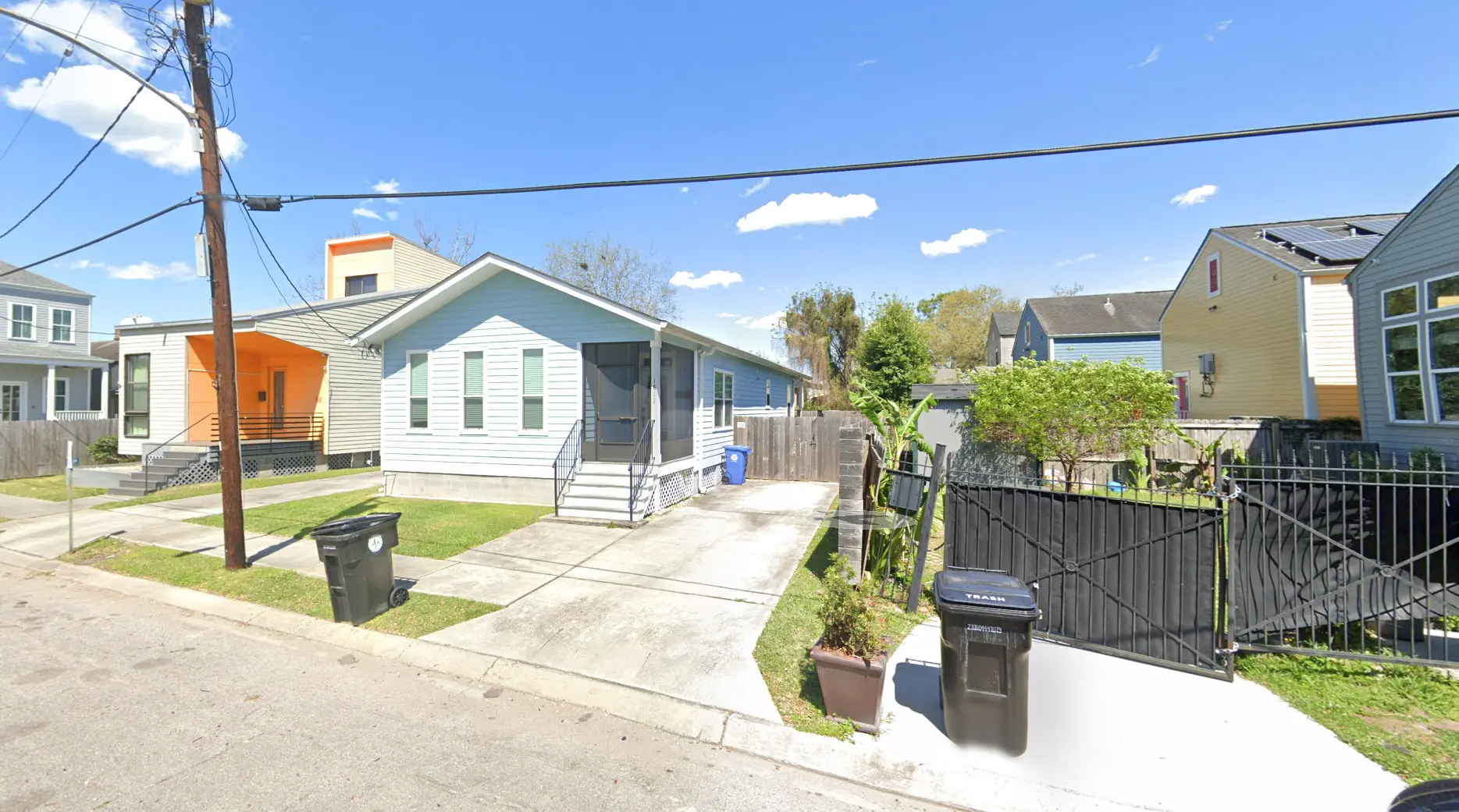 Street view of the light blue 1813 Toledano St home with driveway and fenced yard