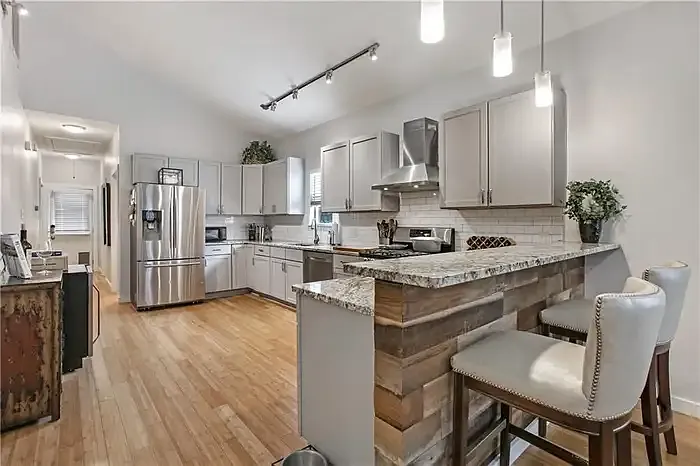 Open kitchen with granite breakfast bar and stainless appliances